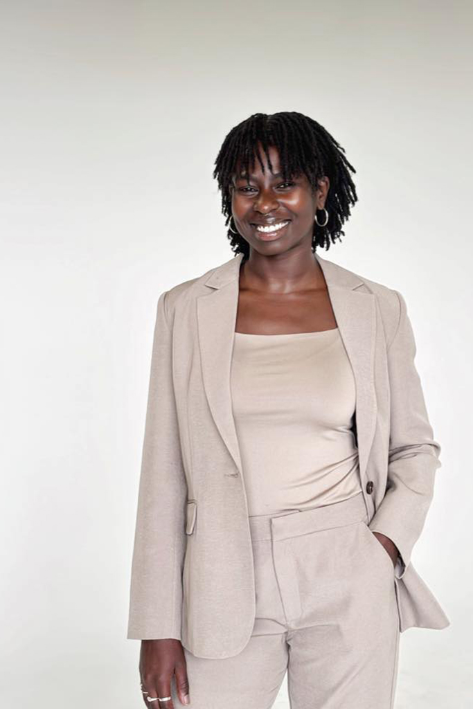 Daphney en mode portrait. Sourire. Complet beige sur arrière plan blanc.